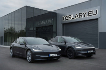 Two dark gray Tesla Model S vehicles parked in front of a modern building with TESLARY.EU signage, under an overcast sky.