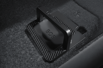 A black SOS emergency locator device with a bright orange handle, resting on a carbon-fiber-textured mat inside a dark carpeted compartment. tesla-model-y-juniper-model-3-highland-rear-door-emergency-handle-mechanical-unlock-for-switch-pull-rope-teslary-dublin-ireland-cork-nederlands-deutschland-espa-5724537_f486ca2e-ada1-4d79-8f2a-5d873537f7f3